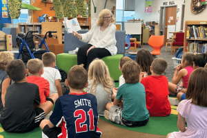 Brookfield Memory Care resients volunteering with the Pewaukee School District, reading books to a group of young children.